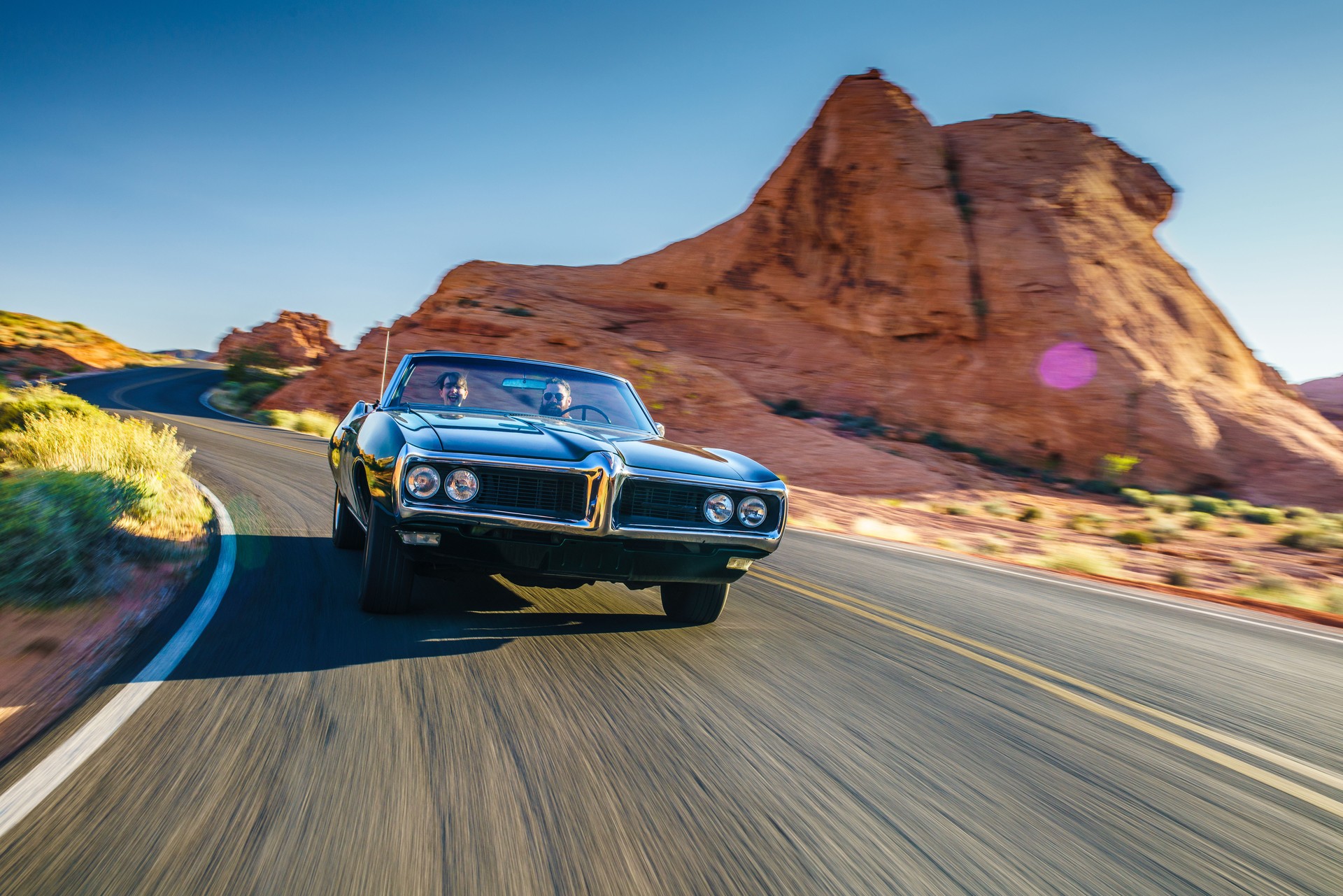 couple driving together in cool vintage car through desert